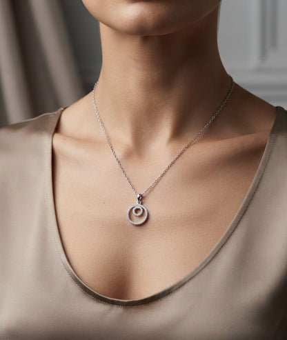 Diamond circle pendant with interlocking open-circle design in 18K white gold, set with round brilliant diamonds.