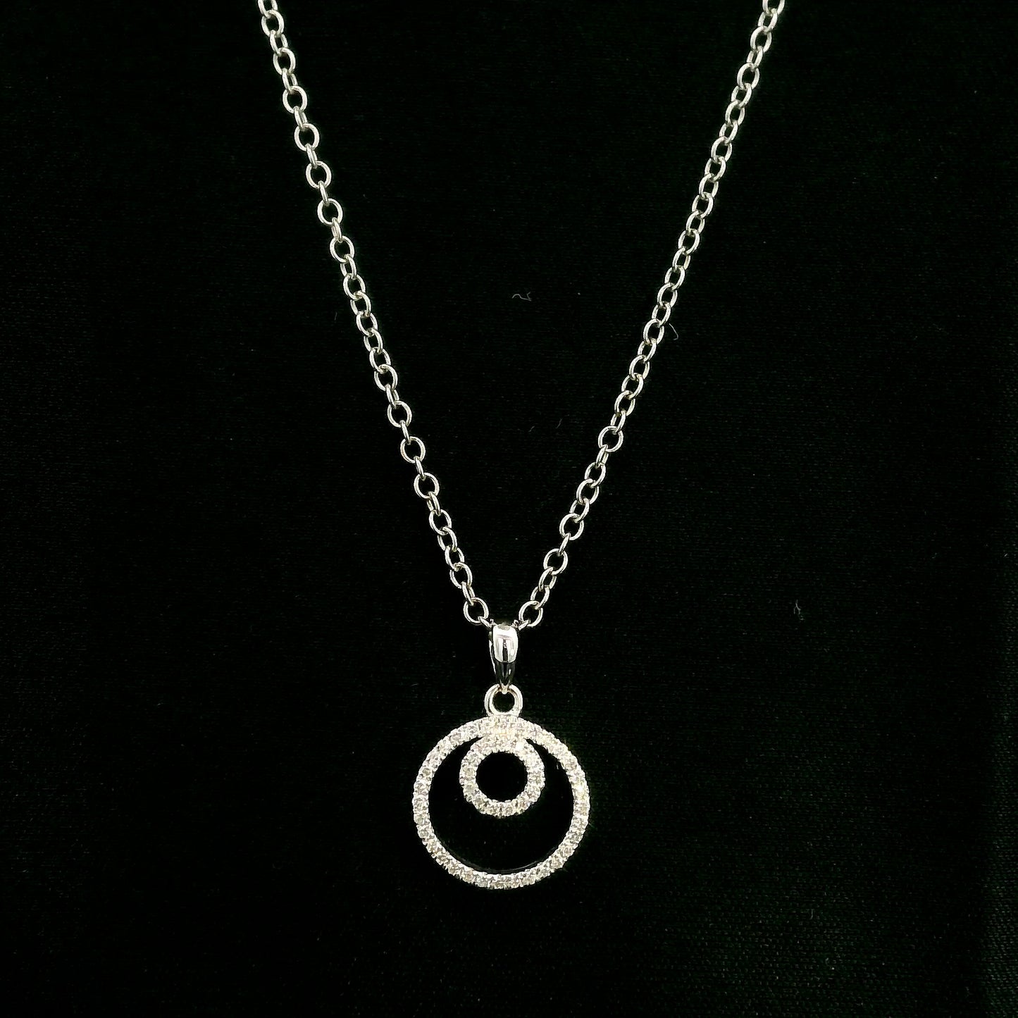 Diamond circle pendant with interlocking open-circle design in 18K white gold, set with round brilliant diamonds.