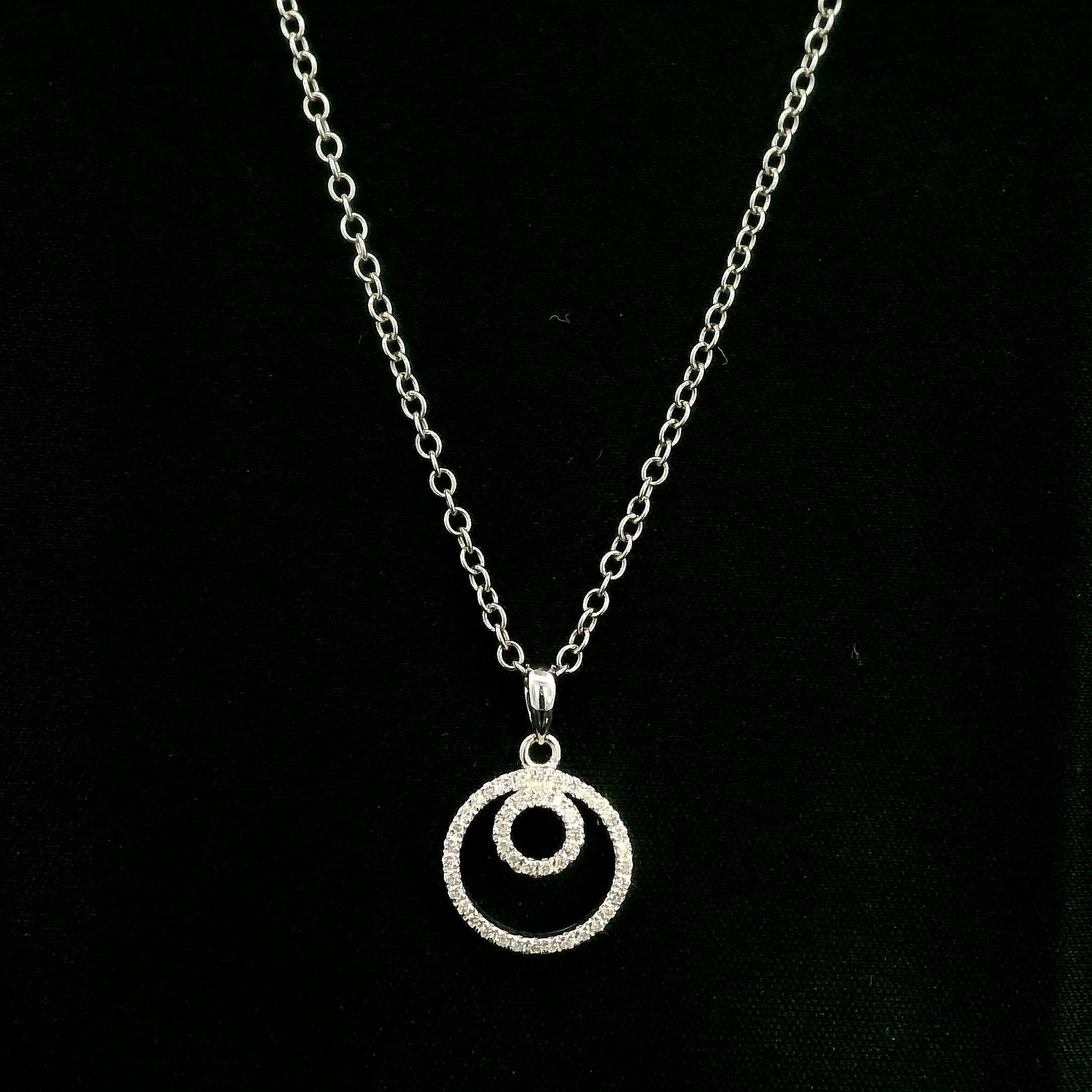 Diamond circle pendant with interlocking open-circle design in 18K white gold, set with round brilliant diamonds.