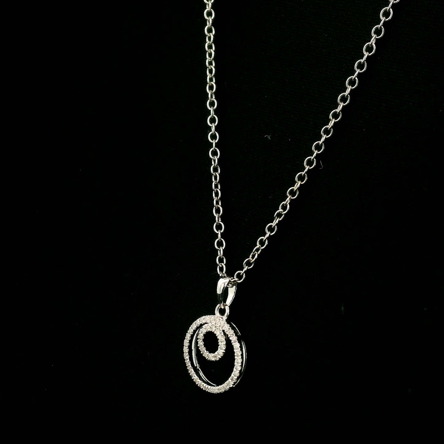 Diamond circle pendant with interlocking open-circle design in 18K white gold, set with round brilliant diamonds.