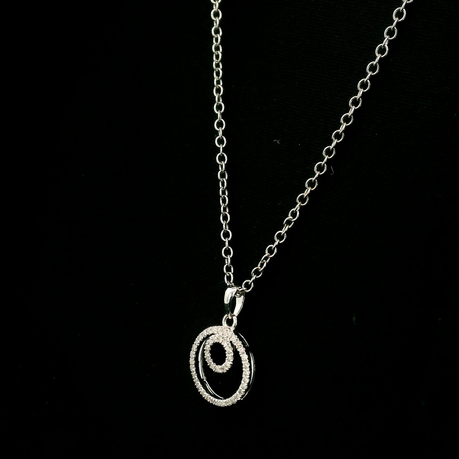 Diamond circle pendant with interlocking open-circle design in 18K white gold, set with round brilliant diamonds.