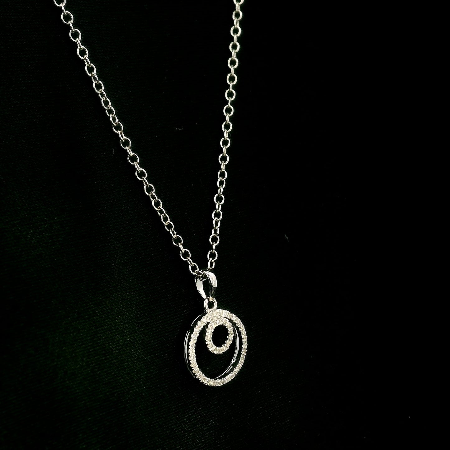 Diamond circle pendant with interlocking open-circle design in 18K white gold, set with round brilliant diamonds.