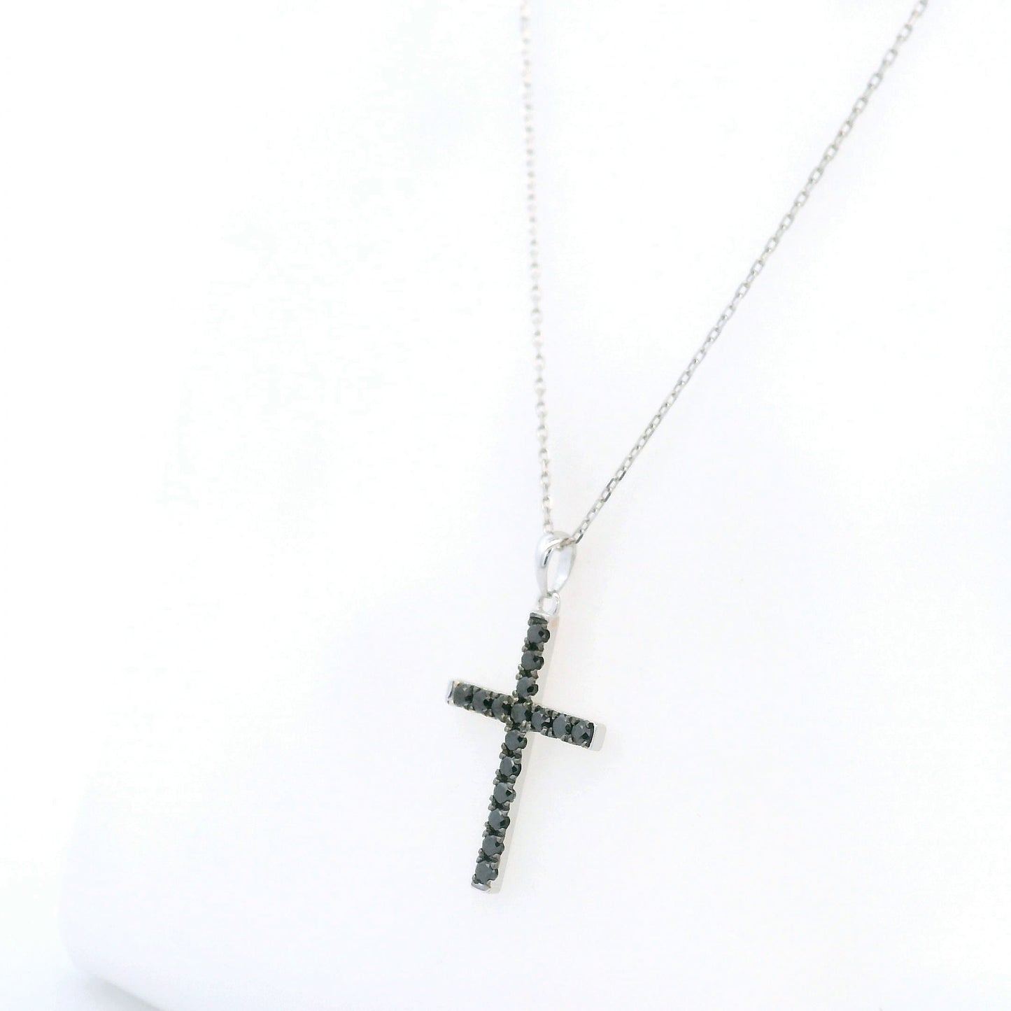 Black diamond cross pendant in 18K white gold set with round black diamonds in a slender cross design.