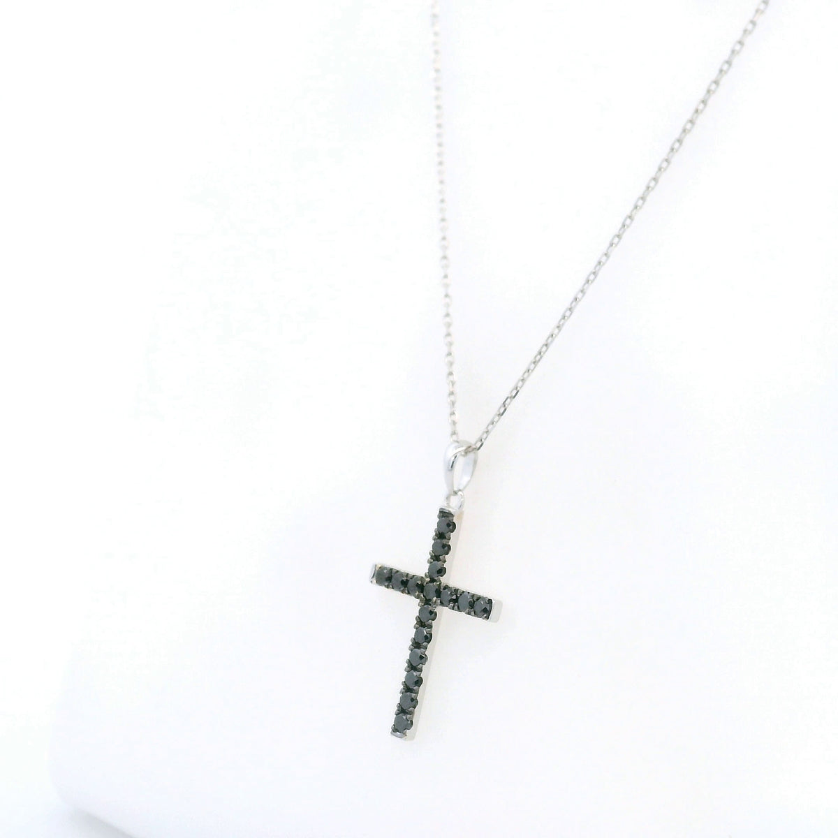 Black diamond cross pendant in 18K white gold set with round black diamonds in a slender cross design.