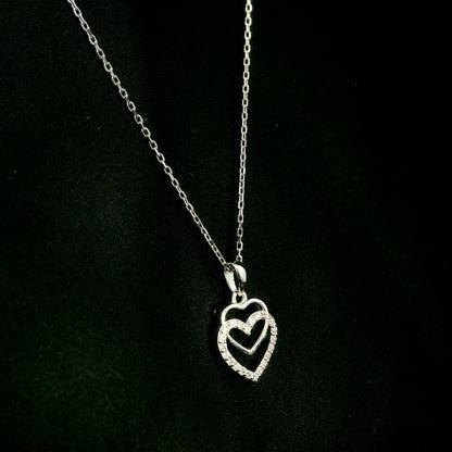 Diamond heart pendant in 18K white gold featuring overlapping open hearts with round brilliant diamond detailing.