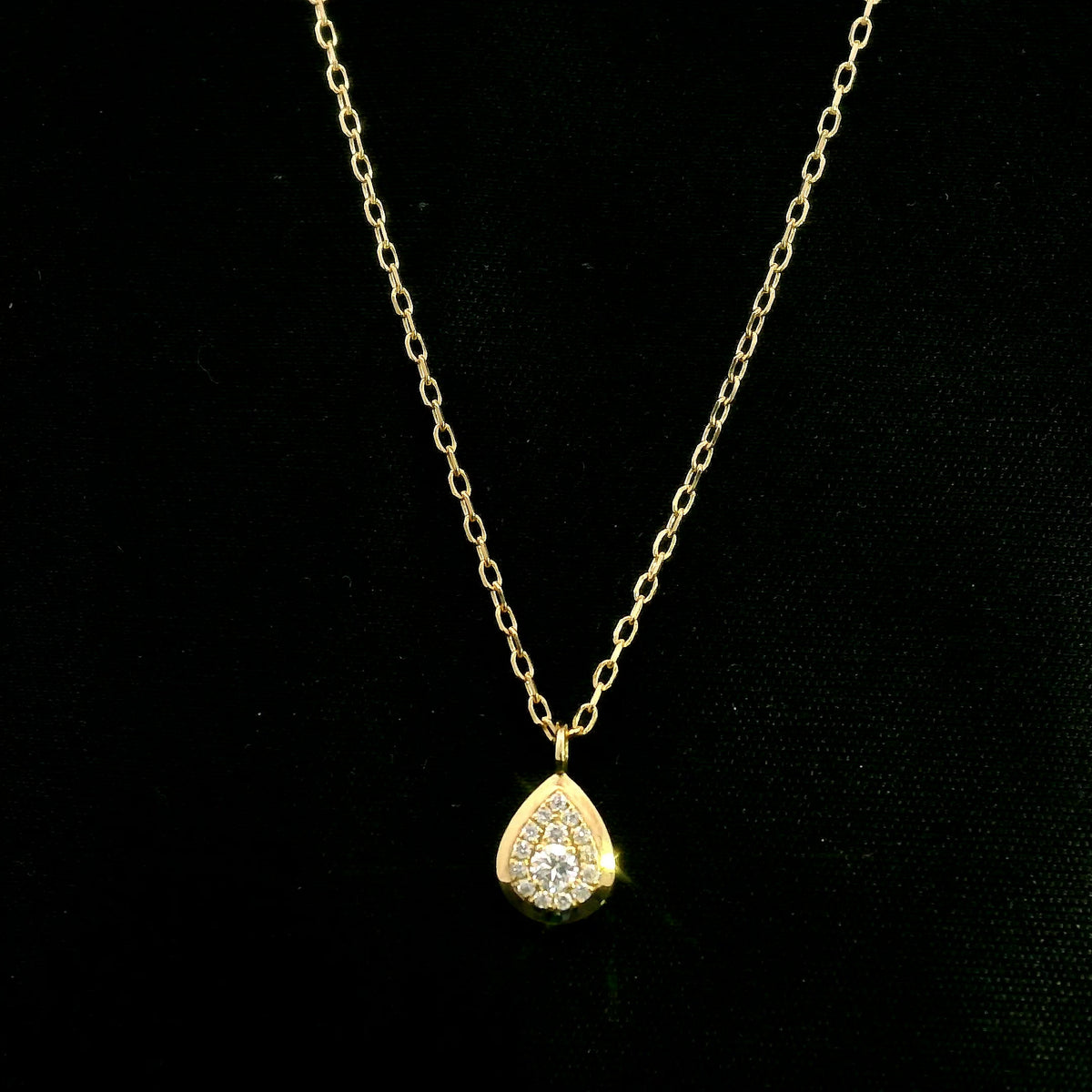 Diamond teardrop pendant necklace in 18K yellow gold featuring round brilliant diamonds arranged within a pear-shaped gold frame.