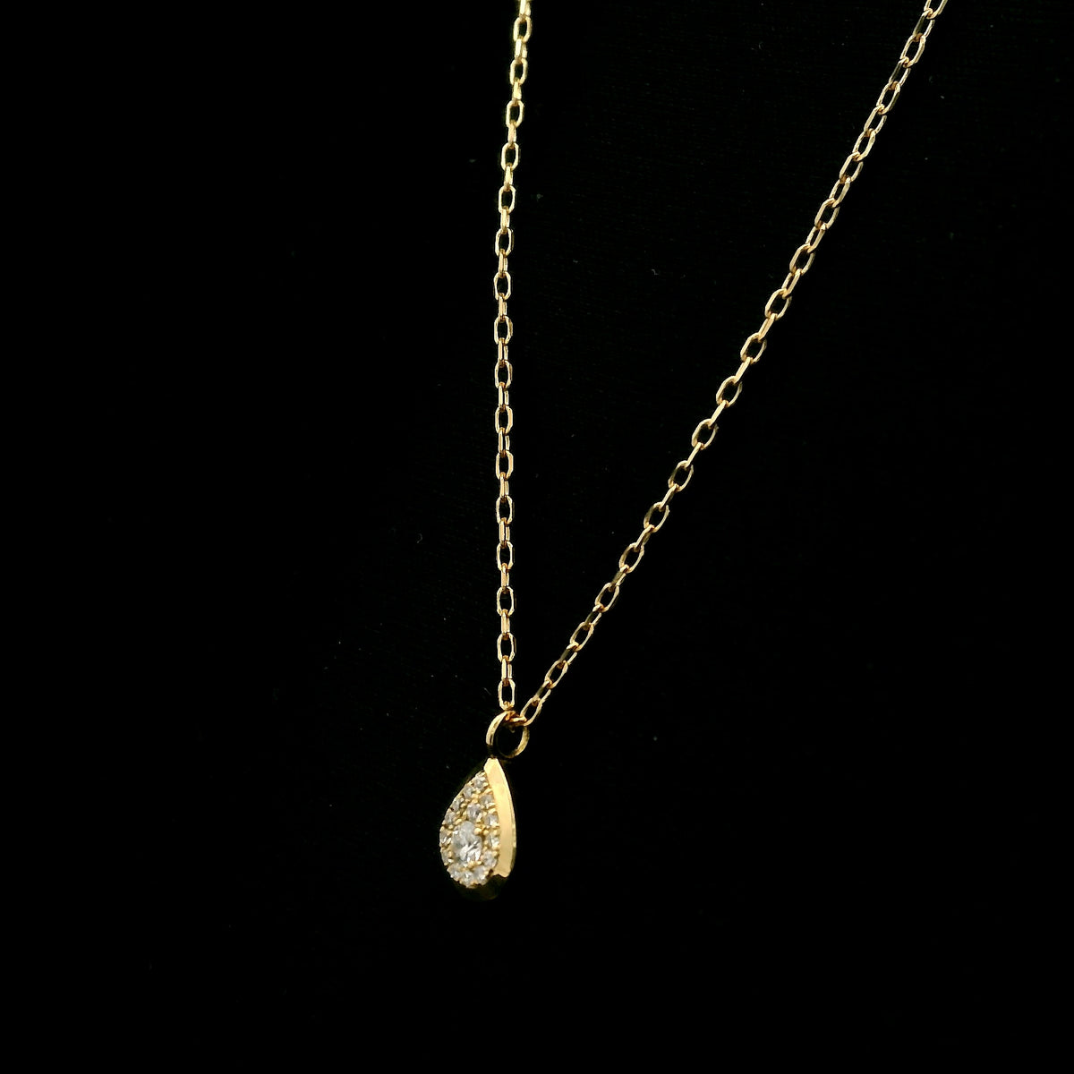 Diamond teardrop pendant necklace in 18K yellow gold featuring round brilliant diamonds arranged within a pear-shaped gold frame.