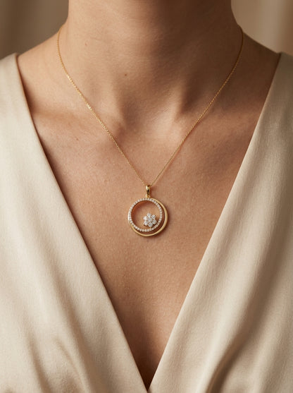 Diamond circle pendant in 18K yellow gold featuring an open circular design with a floral-inspired round diamond cluster and diamond-set curve.