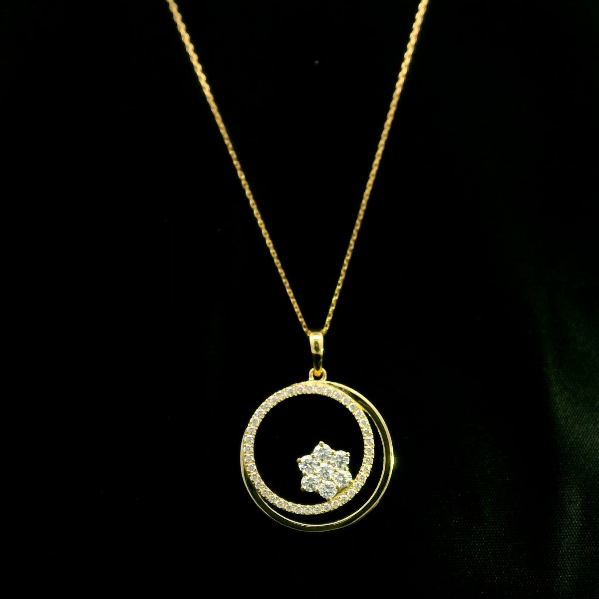 Diamond circle pendant in 18K yellow gold featuring an open circular design with a floral-inspired round diamond cluster and diamond-set curve.
