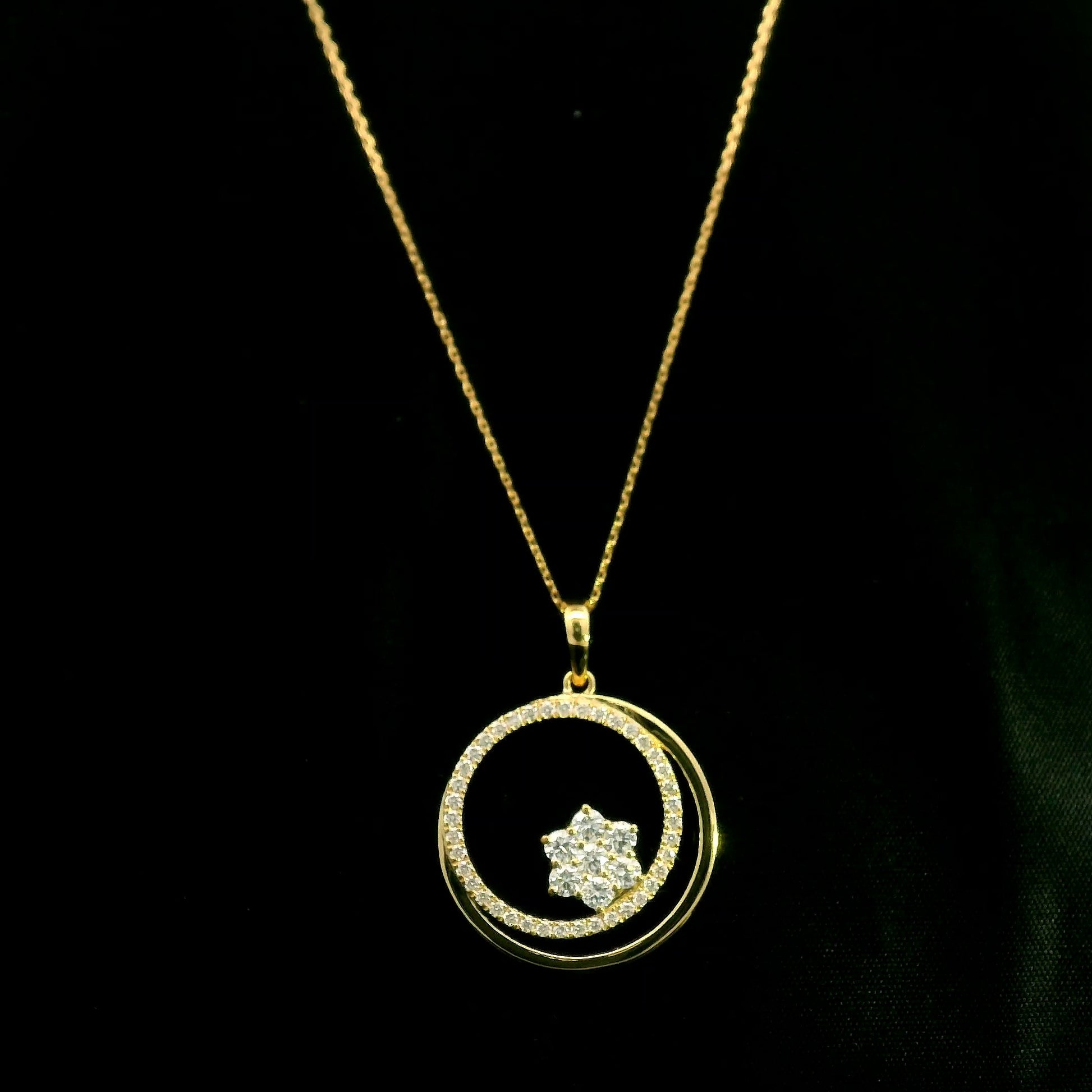 Diamond circle pendant in 18K yellow gold featuring an open circular design with a floral-inspired round diamond cluster and diamond-set curve.