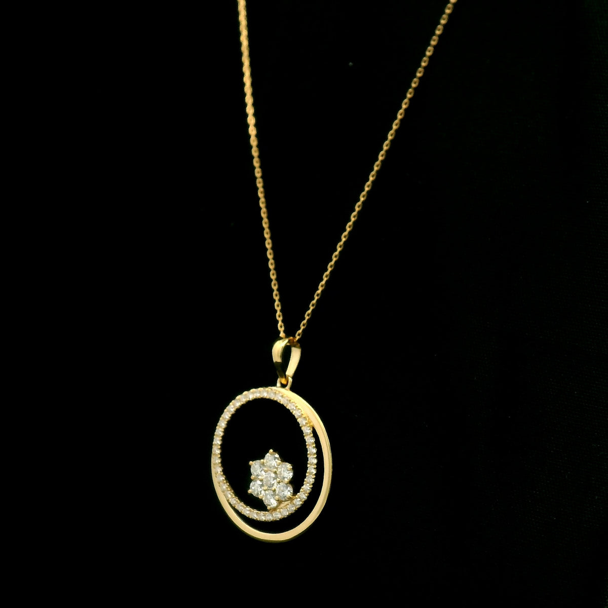 Diamond circle pendant in 18K yellow gold featuring an open circular design with a floral-inspired round diamond cluster and diamond-set curve.