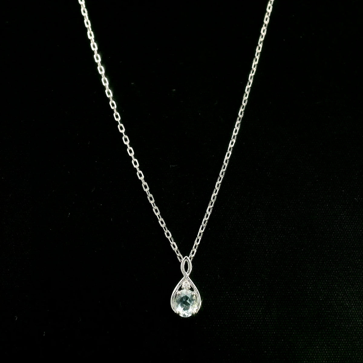 Aquamarine drop pendant necklace in 18K white gold with a round blue aquamarine and delicate diamond accent.