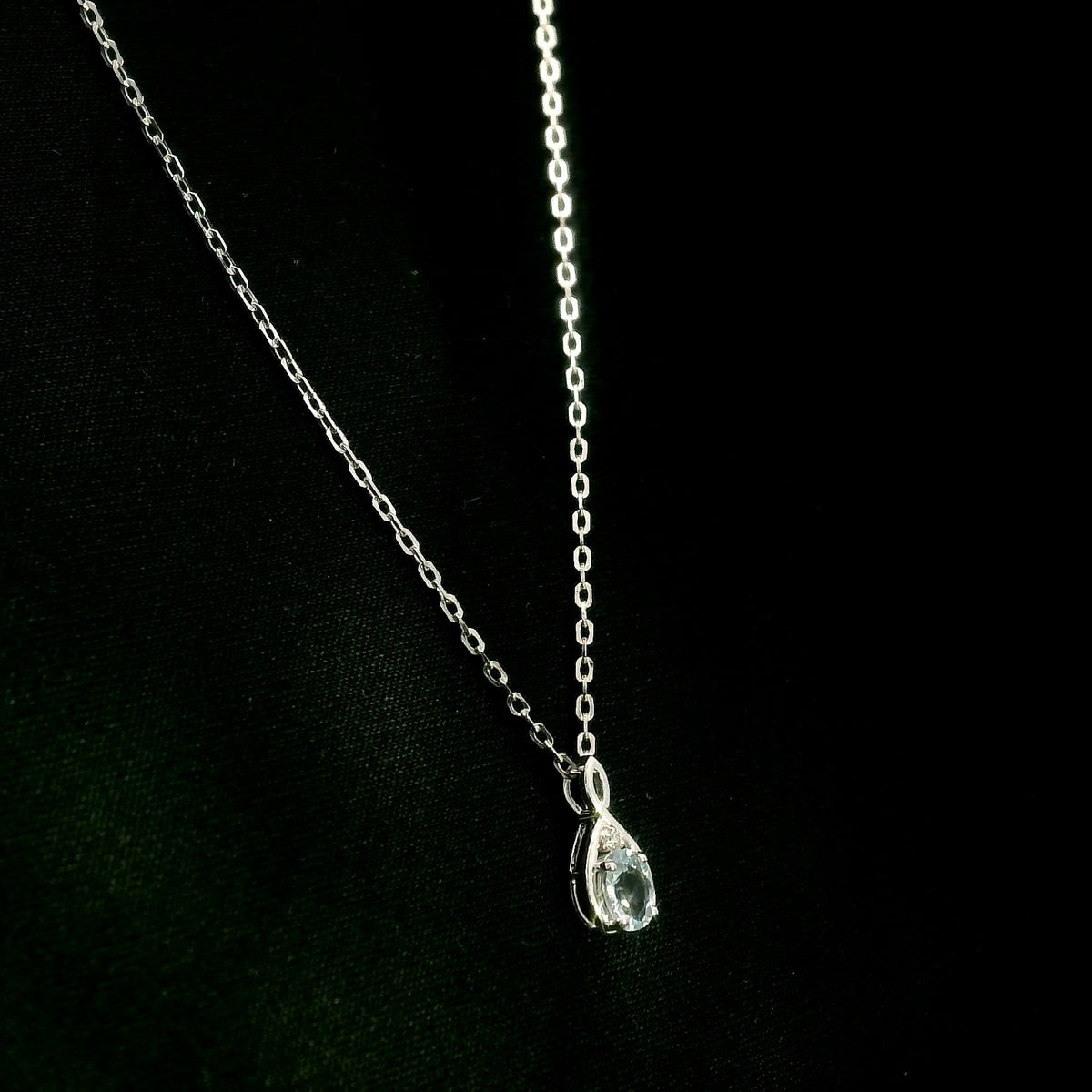 Aquamarine drop pendant necklace in 18K white gold with a round blue aquamarine and delicate diamond accent.