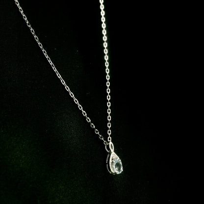Aquamarine drop pendant necklace in 18K white gold with a round blue aquamarine and delicate diamond accent.
