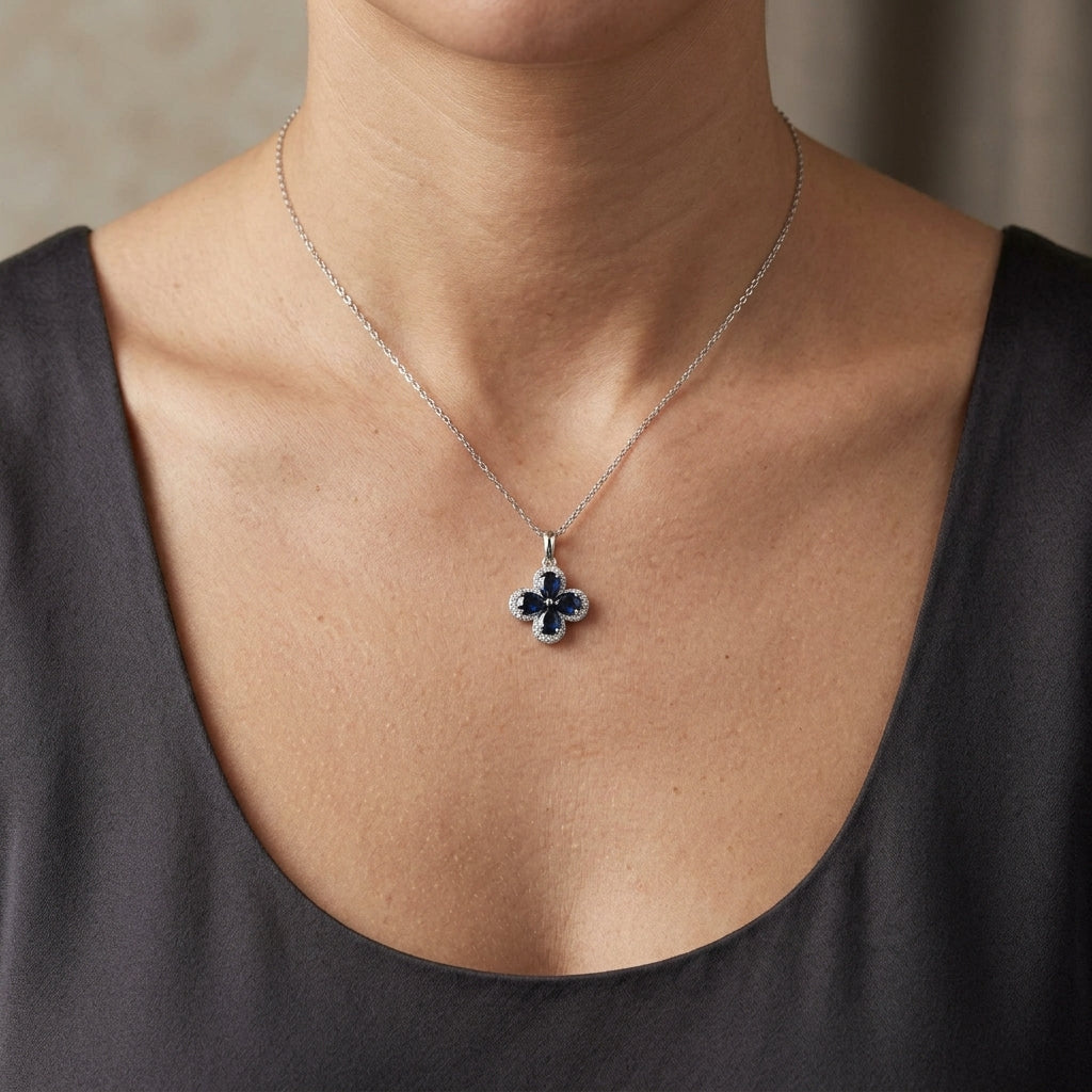 Blue sapphire and diamond floral pendant in 18K white gold featuring four pear-shaped sapphires with diamond surrounds by Emirates Diamonds.