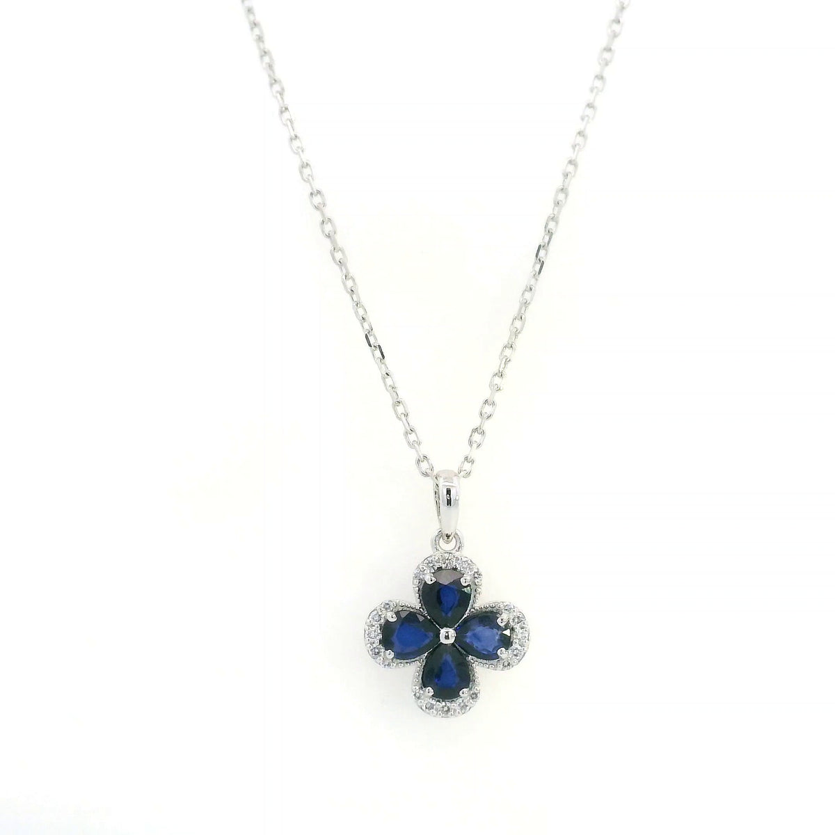 Blue sapphire and diamond floral pendant in 18K white gold featuring four pear-shaped sapphires with diamond surrounds by Emirates Diamonds.