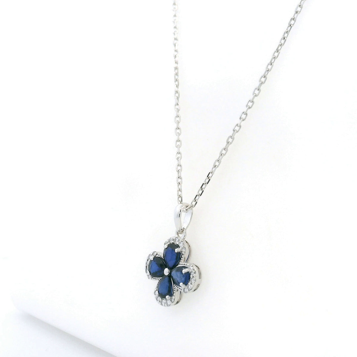 Blue sapphire and diamond floral pendant in 18K white gold featuring four pear-shaped sapphires with diamond surrounds by Emirates Diamonds.