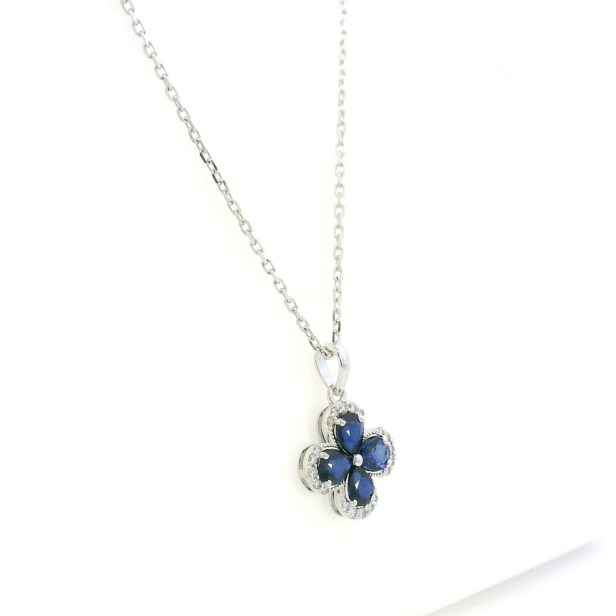 Blue sapphire and diamond floral pendant in 18K white gold featuring four pear-shaped sapphires with diamond surrounds by Emirates Diamonds.