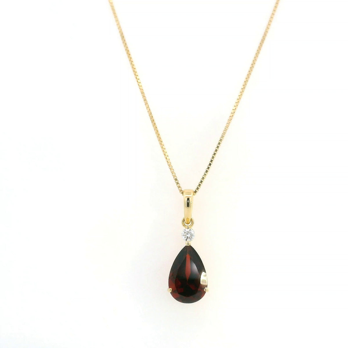 Pear shaped garnet and diamond pendant in 18K yellow gold with a single round diamond accent.