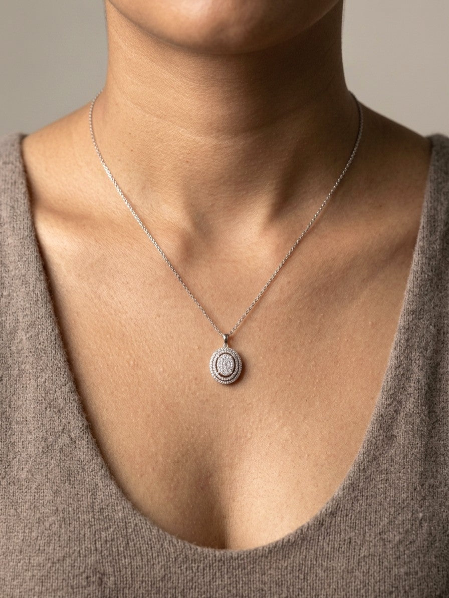 Oval diamond cluster pendant in 18K white gold with a central round diamond cluster and two diamond-set oval surrounds.