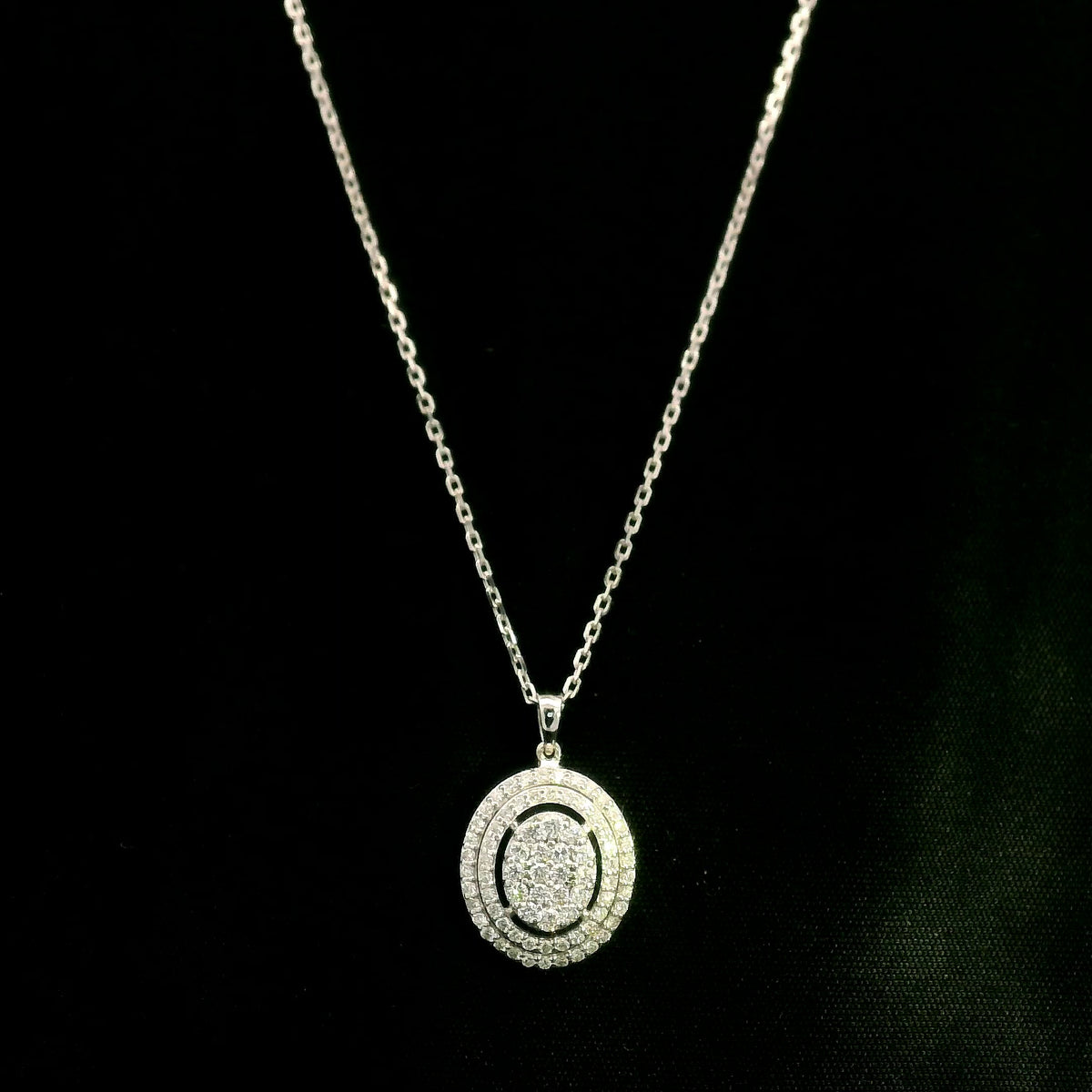 Oval diamond cluster pendant in 18K white gold with a central round diamond cluster and two diamond-set oval surrounds.