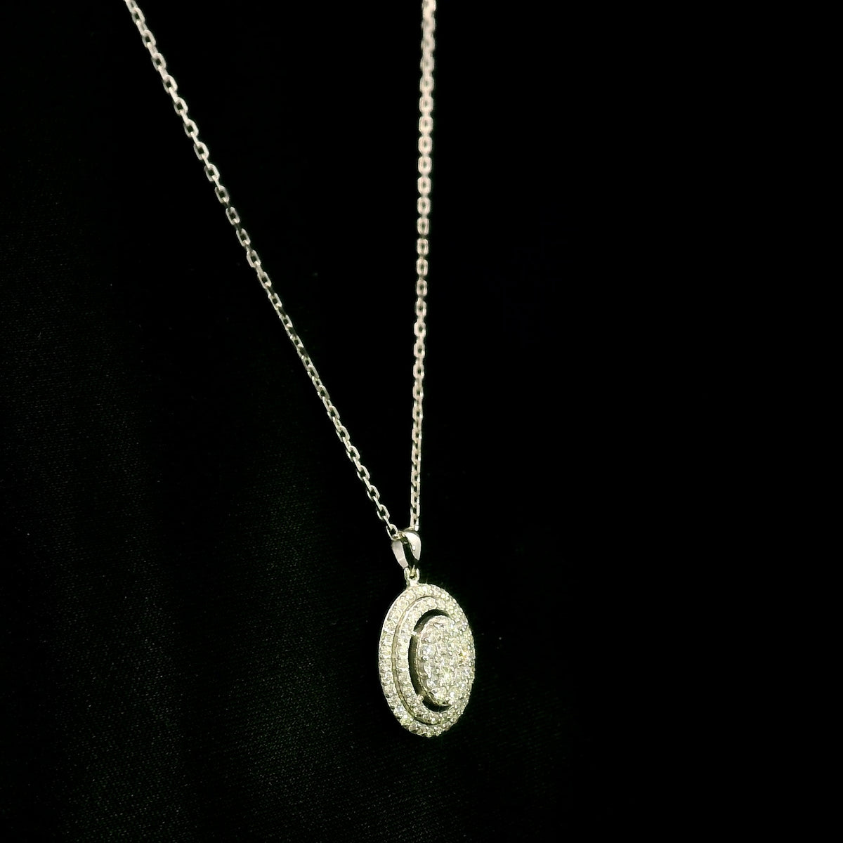 Oval diamond cluster pendant in 18K white gold with a central round diamond cluster and two diamond-set oval surrounds.