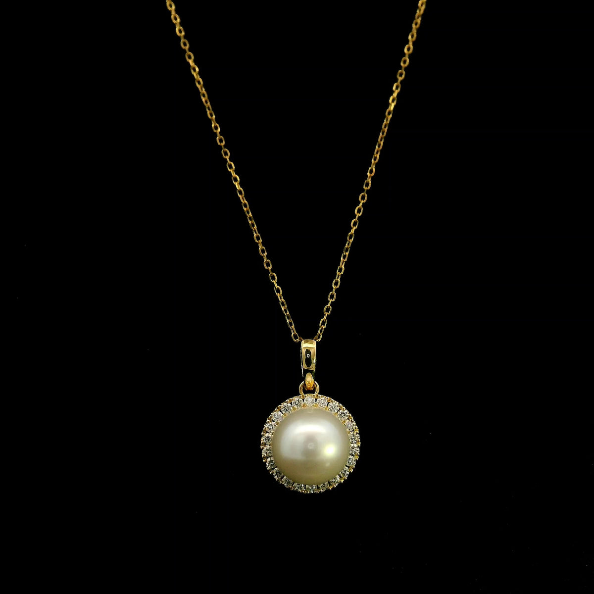 Freshwater white pearl and diamond halo pendant in 18K yellow gold with a round pearl surrounded by brilliant diamonds.