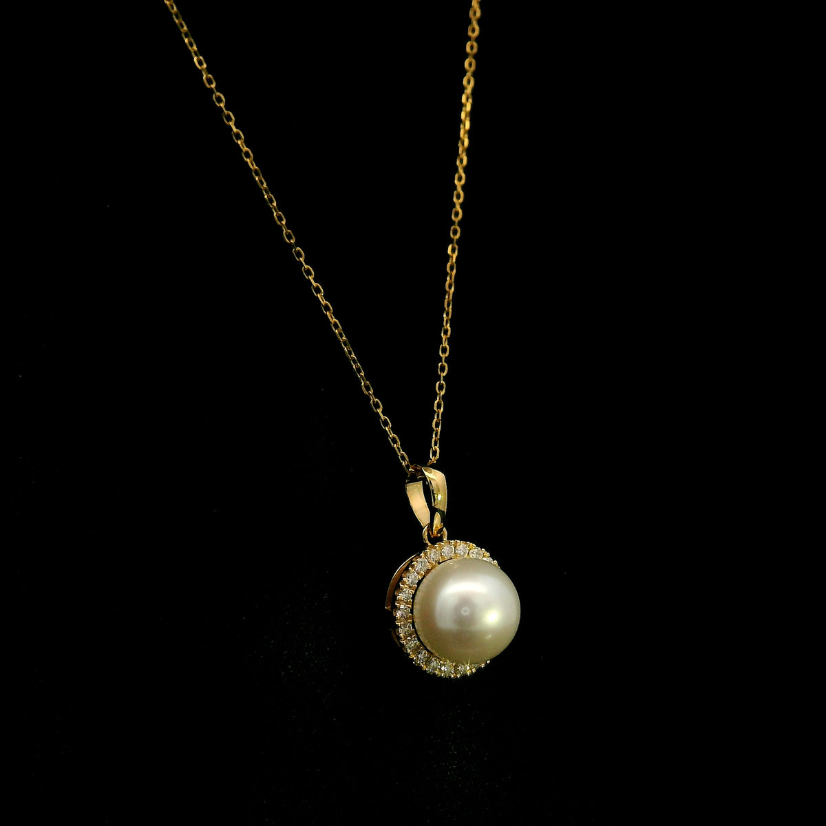 Freshwater white pearl and diamond halo pendant in 18K yellow gold with a round pearl surrounded by brilliant diamonds.