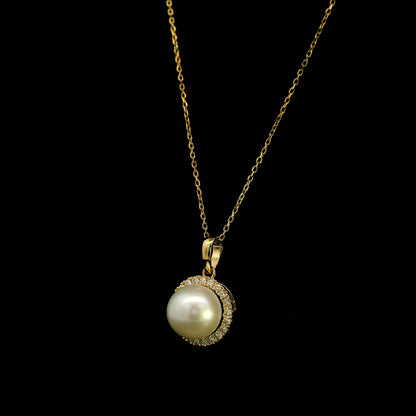 Freshwater white pearl and diamond halo pendant in 18K yellow gold with a round pearl surrounded by brilliant diamonds.