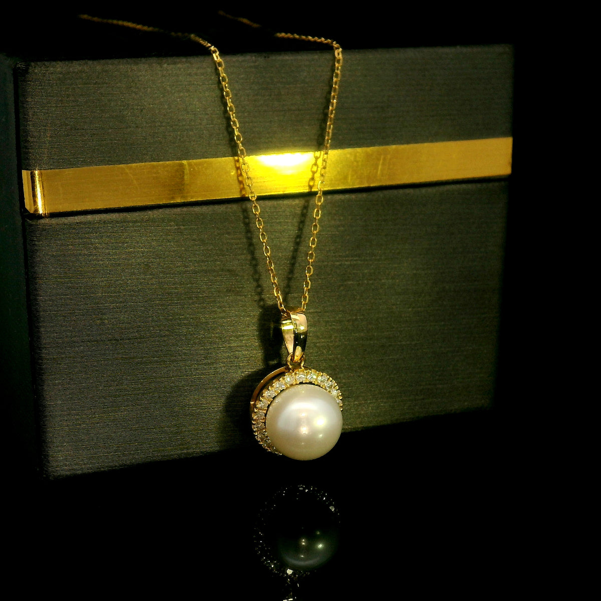 Freshwater white pearl and diamond halo pendant in 18K yellow gold with a round pearl surrounded by brilliant diamonds.