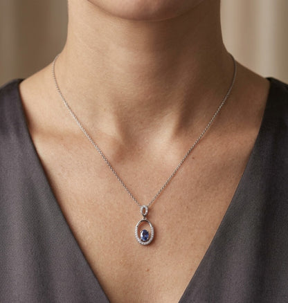 Oval blue sapphire and diamond pendant in 18K white gold with open oval design