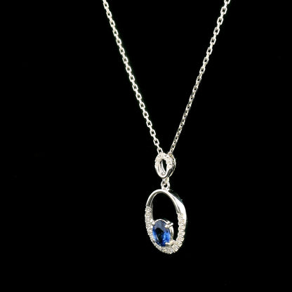 Oval blue sapphire and diamond pendant in 18K white gold with open oval design