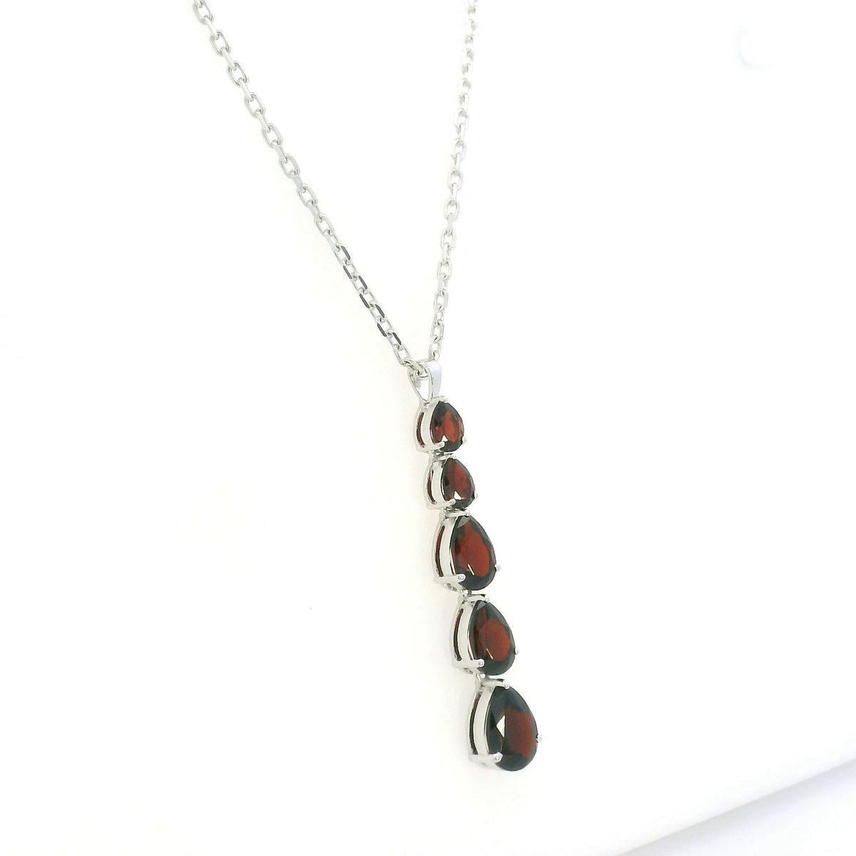 Pear shaped garnet drop pendant in 18K white gold featuring five graduated deep red garnets totalling 2.26 carat, arranged vertically in delicate prong settings. Chain  sold separately 