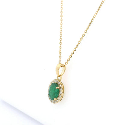 Oval emerald and diamond halo pendant in 18K yellow gold featuring a 1.30 carat green emerald surrounded by round diamonds totalling 0.23 carat. 