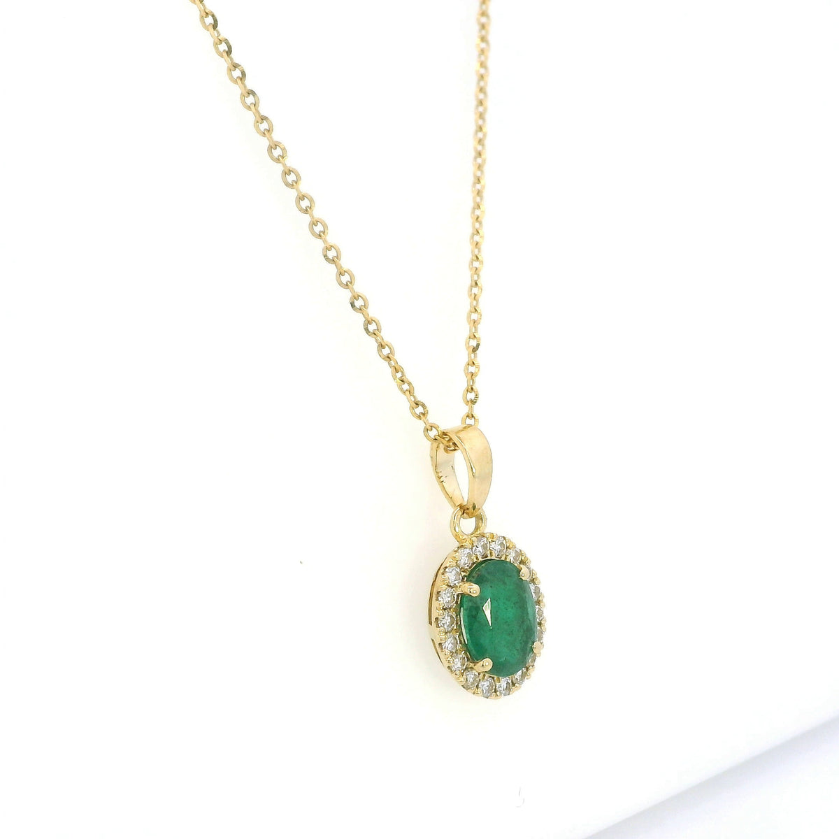 Oval emerald and diamond halo pendant in 18K yellow gold featuring a 1.30 carat green emerald surrounded by round diamonds totalling 0.23 carat. 