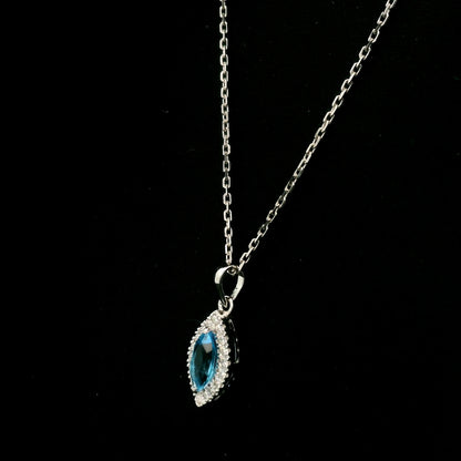 Blue topaz and diamond halo pendant in 18K white gold featuring a 0.70 carat oval blue topaz surrounded by 0.15 carat round diamonds in an elongated marquise-shaped setting, shown with a chain for display.