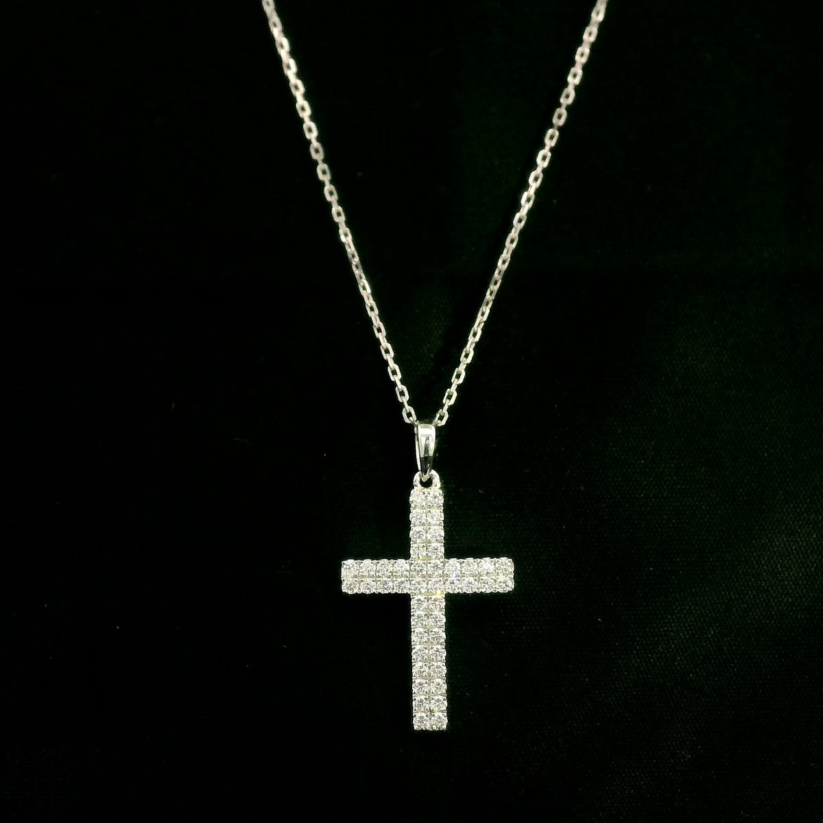 Diamond cross pendant in 18K white gold featuring a traditional cross design covered with multiple rows of round diamonds totalling 0.62 carat, shown on a chain for display.
