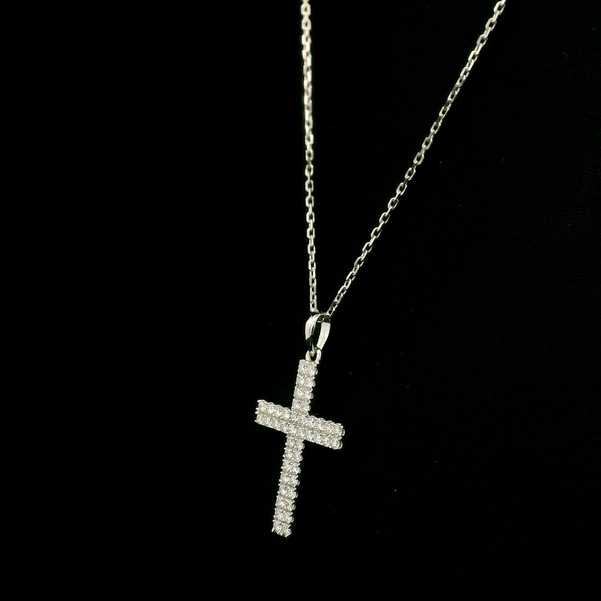 Diamond cross pendant in 18K white gold featuring a traditional cross design covered with multiple rows of round diamonds totalling 0.62 carat, shown on a chain for display.