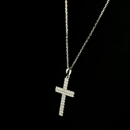 Diamond cross pendant in 18K white gold featuring a traditional cross design covered with multiple rows of round diamonds totalling 0.62 carat, shown on a chain for display.
