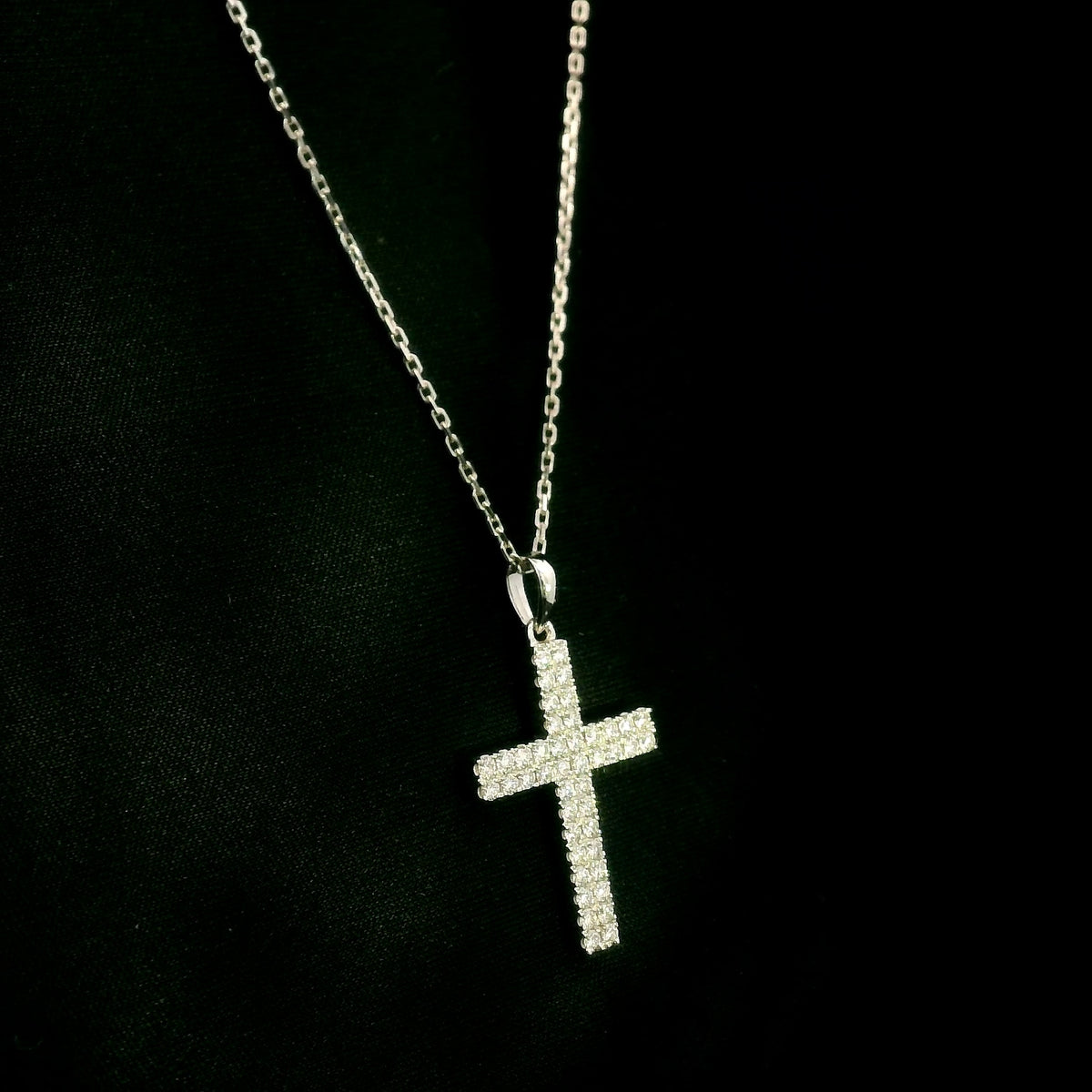 Diamond cross pendant in 18K white gold featuring a traditional cross design covered with multiple rows of round diamonds totalling 0.62 carat, shown on a chain for display.