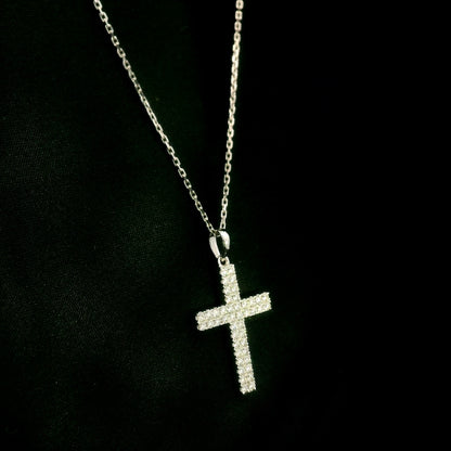 Diamond cross pendant in 18K white gold featuring a traditional cross design covered with multiple rows of round diamonds totalling 0.62 carat, shown on a chain for display.