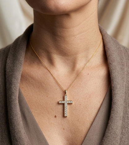 18K yellow gold Christian cross pendant with round diamonds set along the vertical and horizontal arms, shown hanging from a fine gold chain.