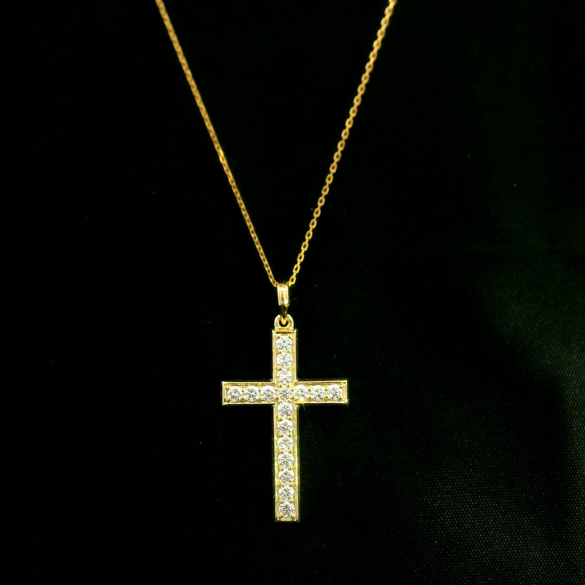 18K yellow gold Christian cross pendant with round diamonds set along the vertical and horizontal arms, shown hanging from a fine gold chain.
