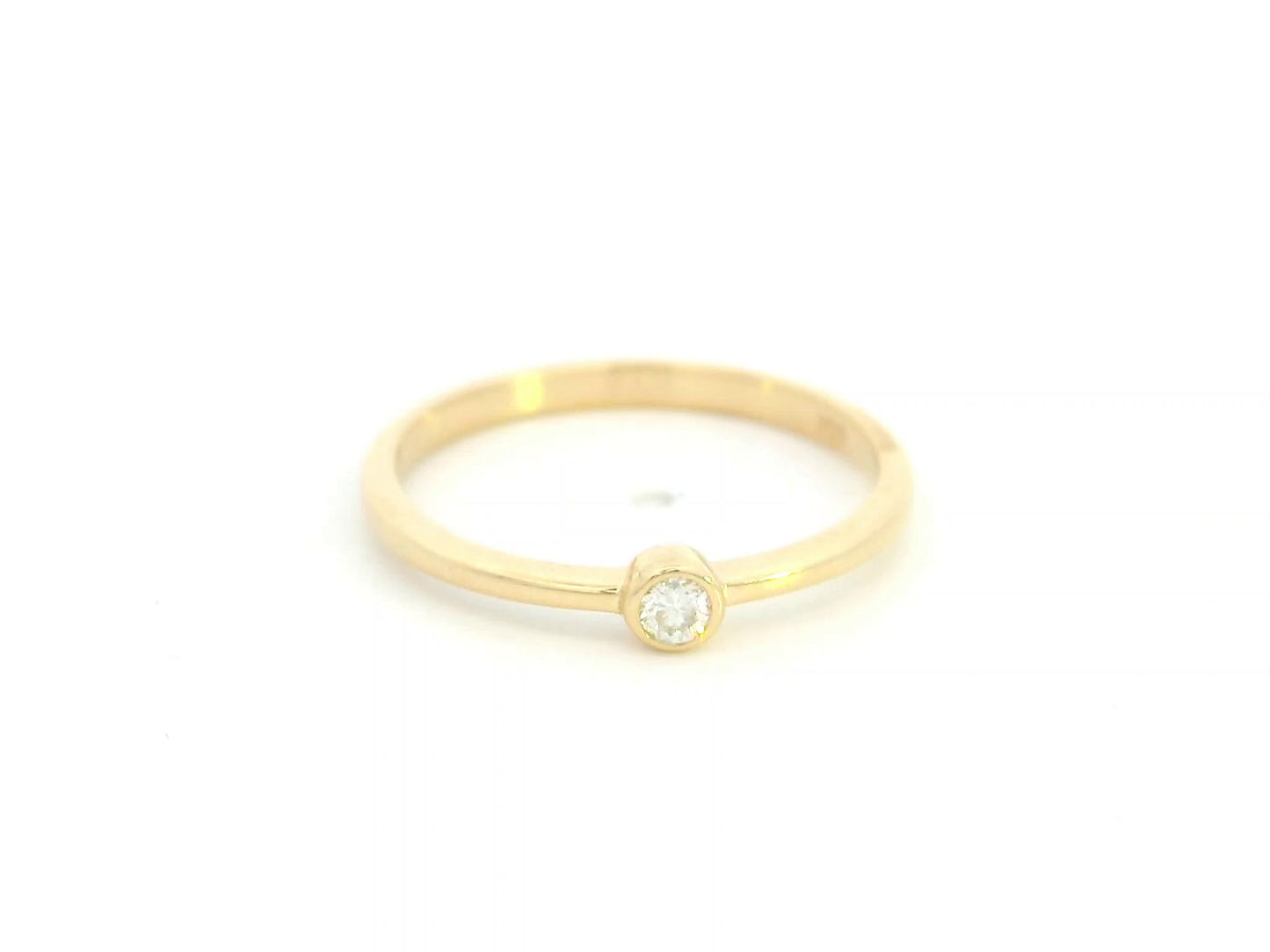 18K yellow gold bezel set diamond ring featuring a 0.07 carat natural round brilliant diamond in a minimalist solitaire design.
