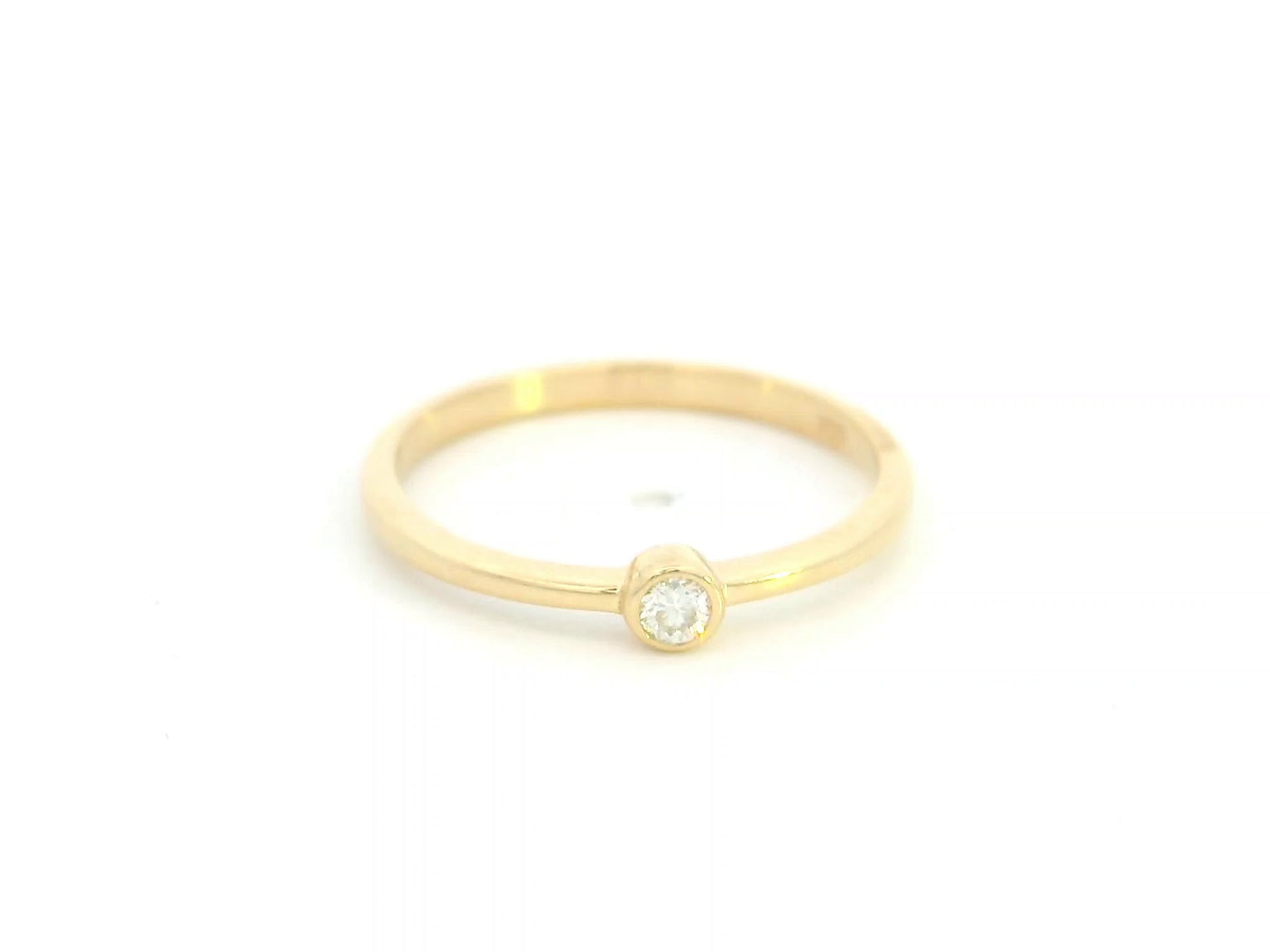 18K yellow gold bezel set diamond ring featuring a 0.07 carat natural round brilliant diamond in a minimalist solitaire design.