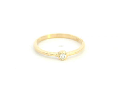 18K yellow gold bezel set diamond ring featuring a 0.07 carat natural round brilliant diamond in a minimalist solitaire design.