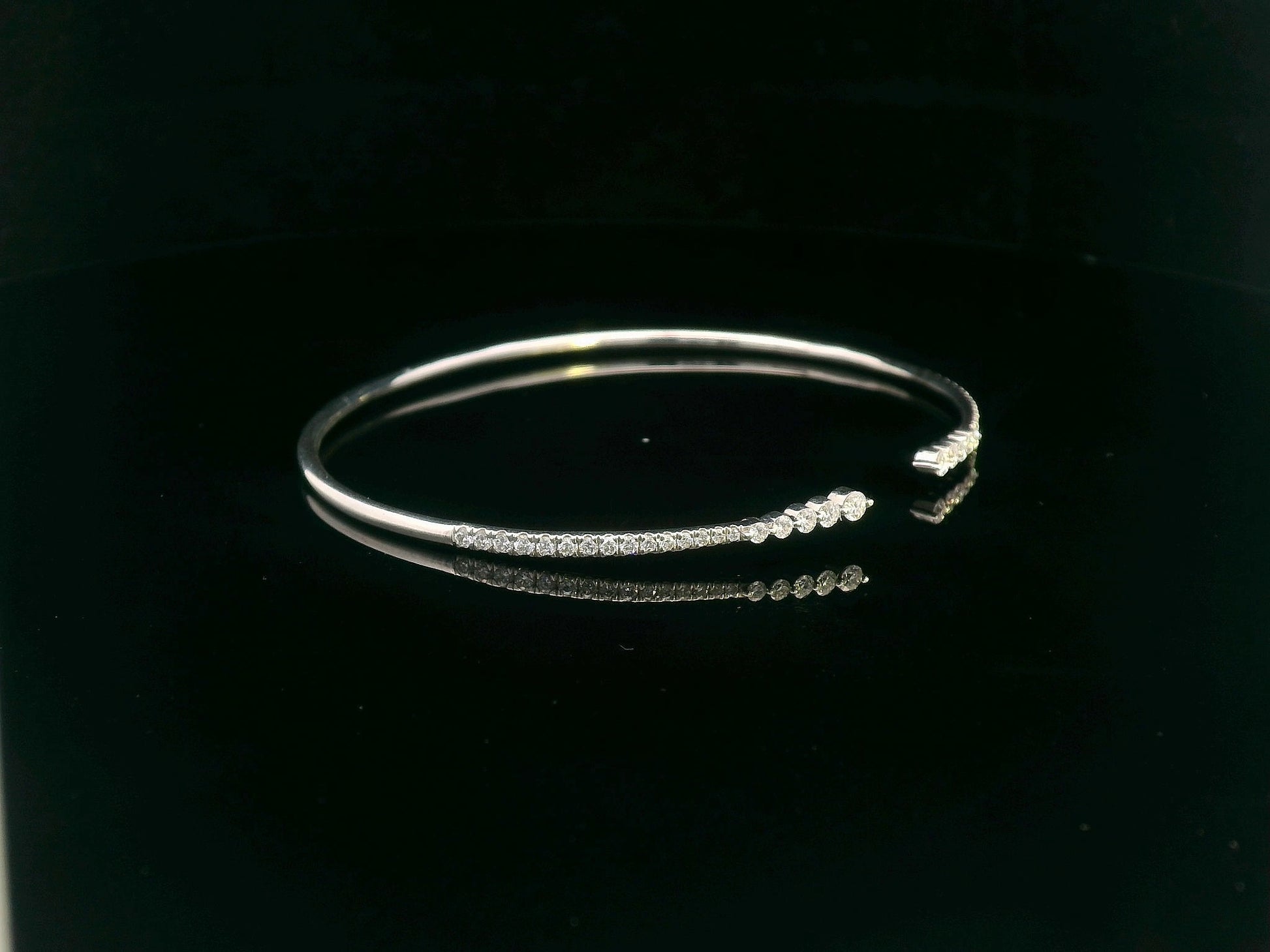 18K gold open diamond bangle bracelet with graduated diamonds, featuring a sleek and modern minimalist design.