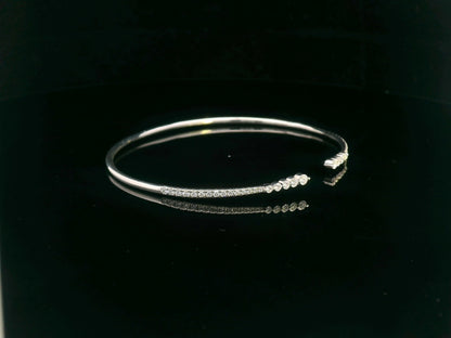 18K gold open diamond bangle bracelet with graduated diamonds, featuring a sleek and modern minimalist design.