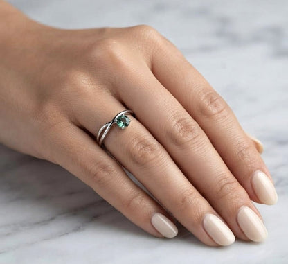 18K white gold crossover ring featuring a natural 0.88 carat round green sapphire in a contemporary solitaire design.