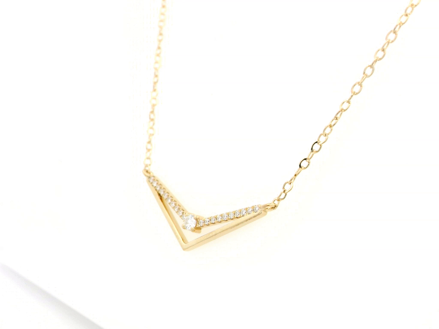 18K gold chevron diamond necklace with 0.16 carats of pavé diamonds on a V-shaped pendant, set on a delicate gold chain.